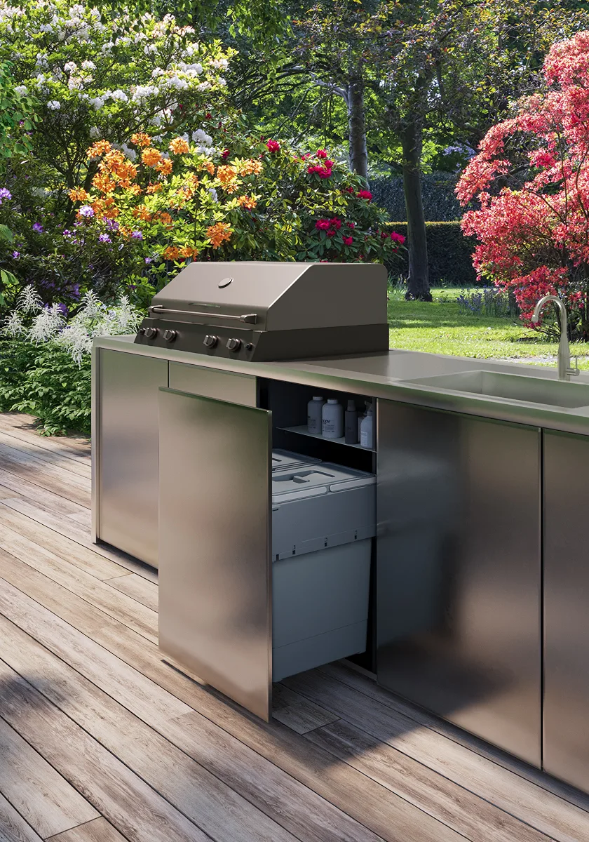 Fotoinserimento di una cucina da esterno in acciaio con barbecue su pedana in giardino